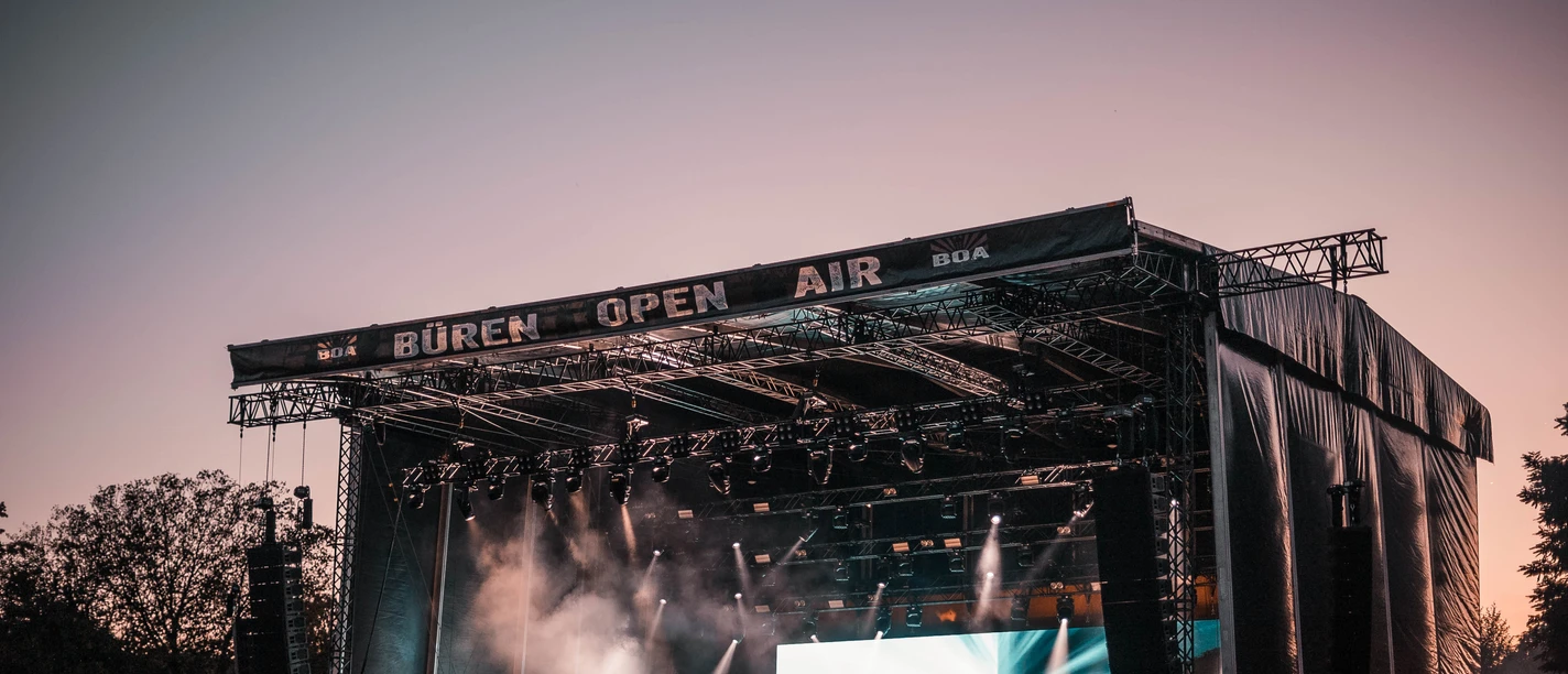 BOA Rocks Großes Freiluftkonzert bei Sonnenuntergang mit Künstlern auf der Bühne und Publikum im Vordergrund.