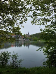 Die Klosterkirche Beyenburg spiegelt sich in einem ruhigen See, umgeben von grüner Landschaft.