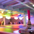 csm_eisspielzeiten-owl_58c81c1c7d.jpg Eine bunte Eishalle mit Besuchern im Hintergrund, im Fokus ein Eisstock mit pinker Griffmanschette.
