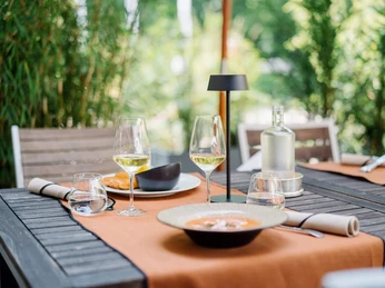 Terrasse im Bistro, Schloss Hugenpoet Ein Tisch im Bistro Schloss Hugenpoet mit eleganter Tischdekoration und Speisen im Freien.
