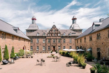 Innenhof vom Schloss Hugenpoet in Essen Historisches Schloss mit Innenhof in Essen, umgeben von Natur, bietet Sitzmöglichkeiten im Freien.