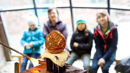 Schauproduktion Glashütte Gernheim.jpg Glasbläser erstellt glühendes Kunstwerk vor Zuschauern in der Glashütte Gernheim.