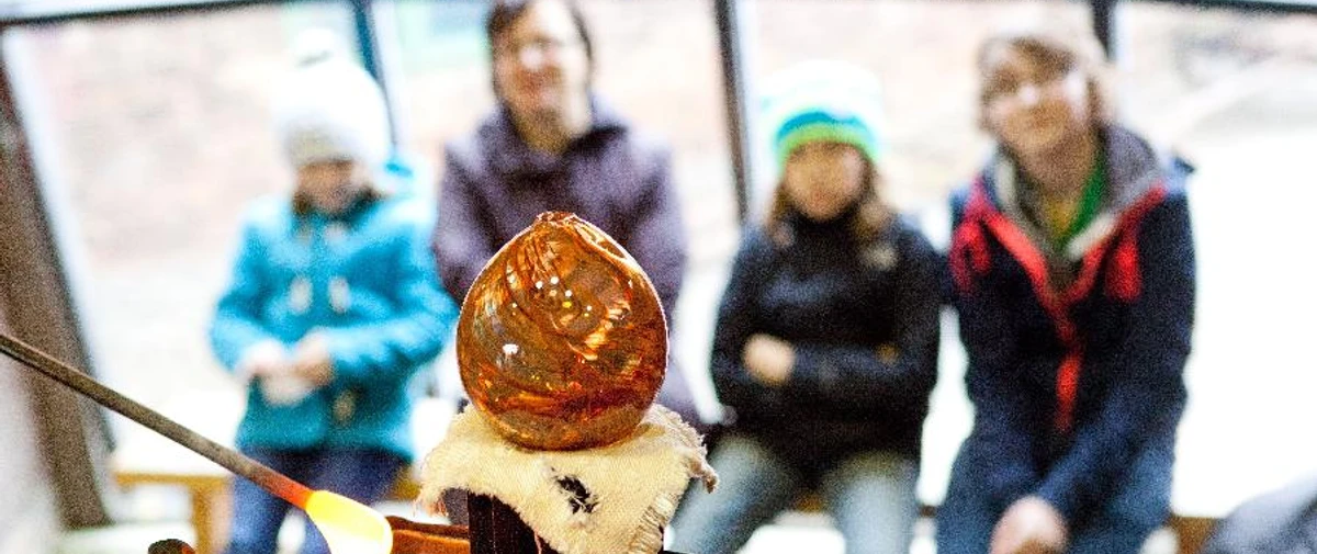 Schauproduktion Glashütte Gernheim.jpg Glasbläser erstellt glühendes Kunstwerk vor Zuschauern in der Glashütte Gernheim.