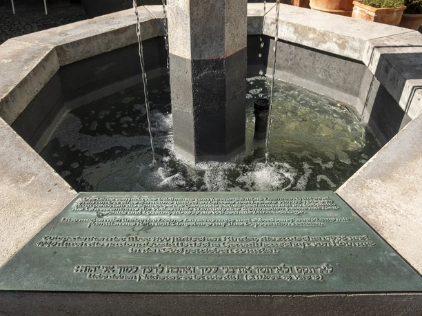 Lion Fountain Hexagonal stone fountain with flowing water, Hebrew inscription on plaque in the foreground.