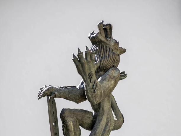 Löwenbrunnen Eine Kupferstatue eines aufrecht stehenden Löwen mit Schild und Schwert, detailreich und imposant.