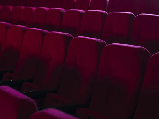 Kino-Sitze Reihen von weichen, roten Sesseln in einem leeren Kinosaal, die einladend auf Besucher warten.
