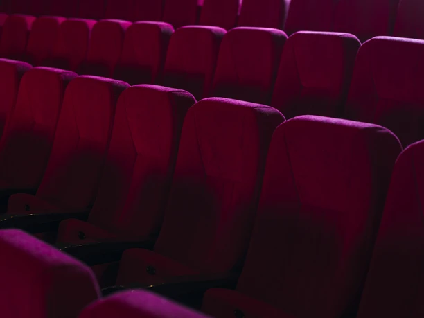 Kino-Sitze Reihen von weichen, roten Sesseln in einem leeren Kinosaal, die einladend auf Besucher warten.