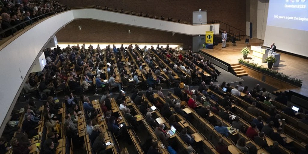 DPG_Frühjahrstagungen Voller AudimaxQuantenjahr 2025 c DPG_Janetzko.jpeg Menschenmenge sitzt im Plenum auf der DPG Frühjahrstagung und schaut zum Vortrag auf der BühneCrowd sits in the plenum at the DPG Spring Conference and watches the lecture on stage