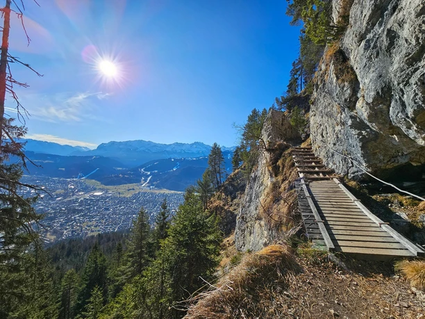 Trail zur Felsenkanzel Schmaler Steg am Fels über bewaldetem Hang mit weitem Blick auf Tal und Berge im Sonnenlicht