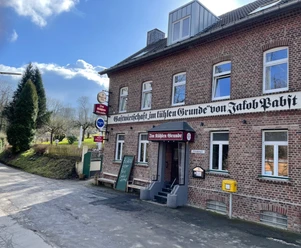 Der Kühle Grund Haan Das Gasthaus bietet traditionelle Küche in einem historischen Backsteingebäude mit rotem Eingang.