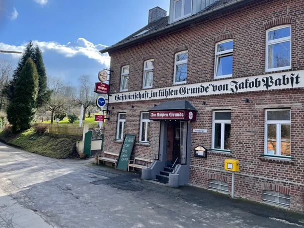 Der Kühle Grund Haan Das Gasthaus bietet traditionelle Küche in einem historischen Backsteingebäude mit rotem Eingang.