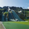 Blick auf die große Olympia Skisprungschanze Große Olympia-Skisprungschanze vor bewaldetem Hang mit mehreren Anlaufspuren bei klarem Licht