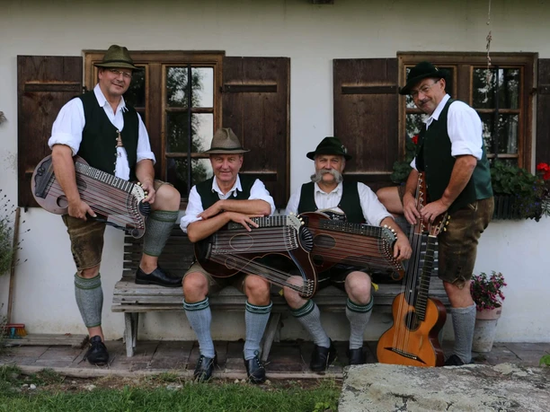 Weinberg-Zithermusi-Volkmusik-Sitzbank-Zithern.jpg Die vier Musikanten der Weinberg Zithermusi mit Instrumenten