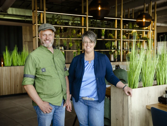 2-Betreiber.jpg Ein Mann und eine Frau lächeln in einem modernen, grün dekorierten Restaurant.