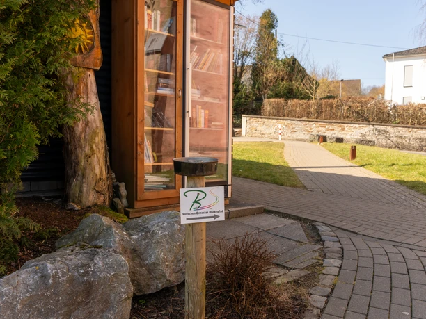 Wegezeichen Welschen Ennester Blickepfad Das Wegezeichen mit Pfeil, weist den Weg des Blickepfades. Es ist an einem halbhohen Pfosten am Wegesrand am Dorfplatz montiert.
