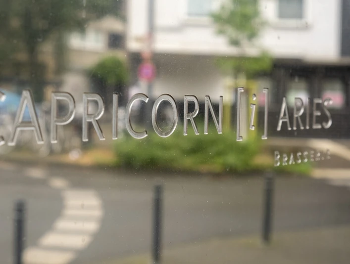 Brasserie Capricorn i aries In großen Lettern steht der Restaurantname auf einem Schild.The restaurant's name is written in large letters on a sign.