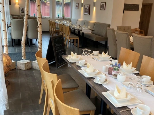 Ein einladendes Café mit hellen Holzmöbeln, stilvoll gedeckten Tischen und moderner Inneneinrichtung.