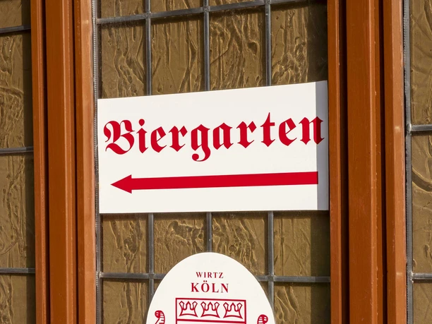 Brauhaus Schreckenskammer Ein Fenster des Brauhauses Schreckenskammer in Köln mit einem Schild, das auf den Biergarten hinweist.
