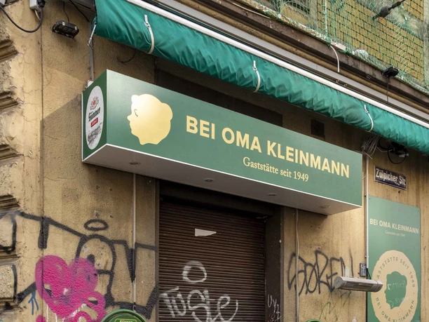 Bei Oma Kleinmann Restaurant Eingang zum Restaurant in urbaner Umgebung mit Graffiti an den Wänden und Restaurantschild über dem Eingang.