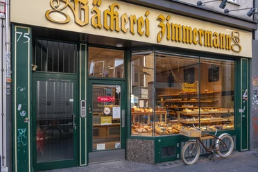 Außenansicht auf die Bäckerei. Im Schaufenster liegen Backwaren und ein Fahrrad steht davor.