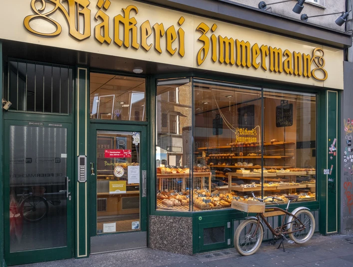 Bakery Zimmermann Außenansicht auf die Bäckerei. Im Schaufenster liegen Backwaren und ein Fahrrad steht davor.Exterior view of the bakery. Baked goods are in the shop window and a bicycle is in front of it.