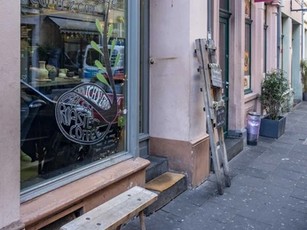 Cafe Hommage Rosefarbende Hausfassade mit großem Fenster zum Cafe.Rose-colored house facade with a large window to the cafe.