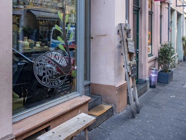 Cafe Hommage Rosefarbende Hausfassade mit großem Fenster zum Cafe.