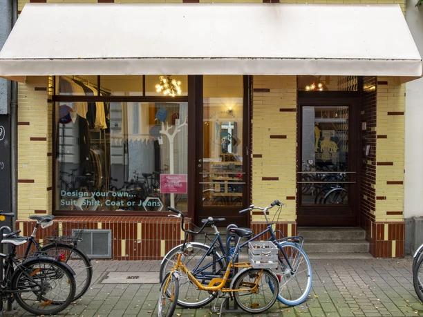 Herrenbude The front view of an old building with a yellow brick façade and large windows. Several bicycles are parked on the sidewalk in front of the entrance.