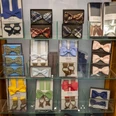Herrenbude Ein Regal mit sorgfältig angeordneten, farbenfrohen Herrenfliegen in verschiedenen Mustern und Materialien, präsentiert in Boxes und auf Glasregalen.A shelf with carefully arranged, colorful men's bow ties in various patterns and materials, presented in boxes and on glass shelves.