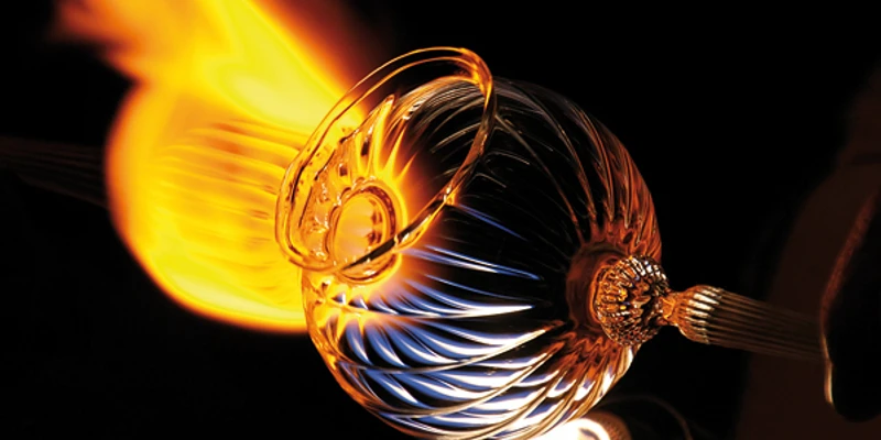 windlicht-live_600.jpg Ein Glasbläser formt ein glühendes, spiralförmig gemustertes Glasobjekt vor Flammenhitze.