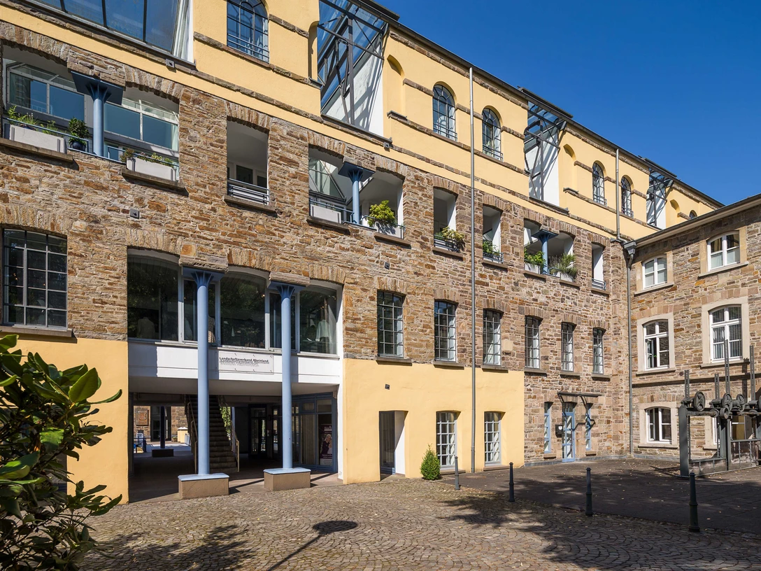 Außenführung Fassadenansicht eines historischen Gebäudes aus gelbem und braunem Stein, Innenhof mit gelben Wänden.