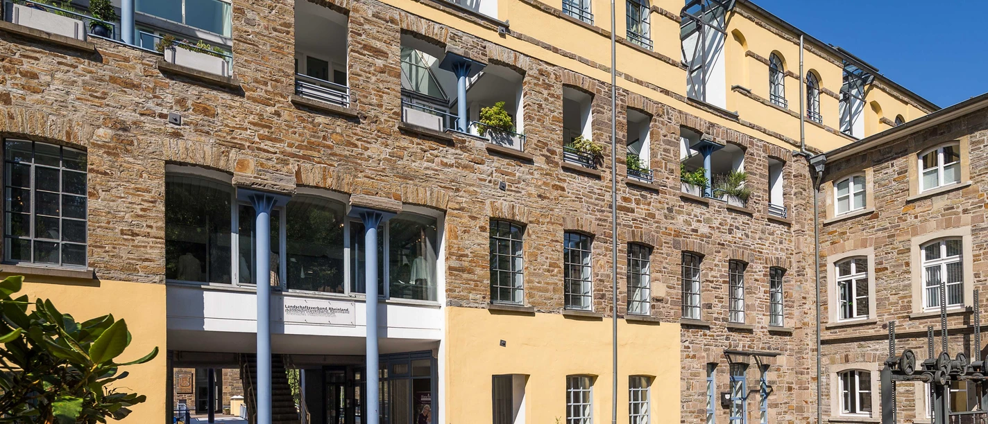 Außenführung Fassadenansicht eines historischen Gebäudes aus gelbem und braunem Stein, Innenhof mit gelben Wänden.