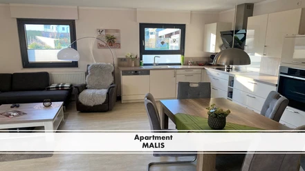 Apartment MALIS Modernes Apartment mit offenem Wohnbereich, heller Küchenzeile, Essbereich und bequemen Sitzmöbeln.