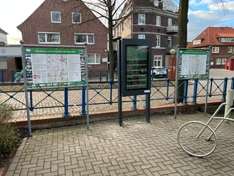 A modern outdoor information kiosk provides digital information against the backdrop of traditional brick architecture.