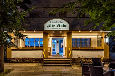 Eingang vom Landhotel Alte Linde Würgassen Beleuchteter Eingang mit drei Treppenstufen und Geländer, seitlich rechts Terrassenbestuhlung