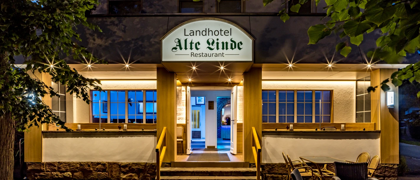 Eingang vom Landhotel Alte Linde Würgassen Beleuchteter Eingang mit drei Treppenstufen und Geländer, seitlich rechts Terrassenbestuhlung