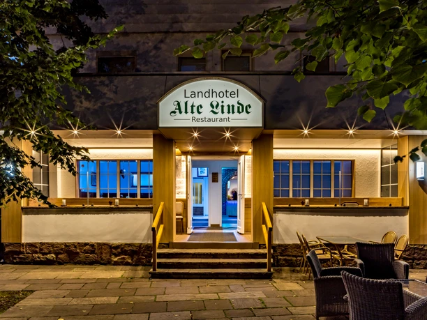 Eingang vom Landhotel Alte Linde Würgassen Beleuchteter Eingang mit drei Treppenstufen und Geländer, seitlich rechts Terrassenbestuhlung