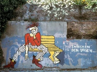 Street Art Führung-Aachener Innenstadt Zwischen den Tagen (c) Regina Weinkauf.jpg Graffiti einer Punk-Person auf einer Bank mit der Aufschrift „Zwischen den Tagen“ vor einer alten Mauer.