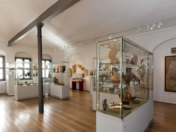 Ausstellungsstücke im Antikenmuseum der Universität Leipzig - Museen im Leipzig Im hellen Ausstellungsraum des Antikenmuseums der Universität Leipzig befinden sich mehrere Glasvitrinen mit antiken Vasen, Schalen und Büsten