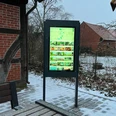Infoterminal Landesbergen Ein moderner Infoterminal mit leuchtendem Display im Außenbereich, umgeben von schneebedeckten Strukturen.