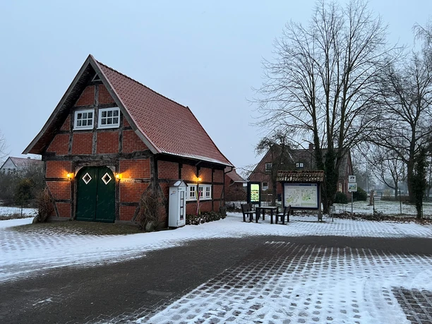 Infoterminal Landesbergen Historisches Fachwerkgebäude am Infoterminal Landesbergen mit schneebedecktem Hof und kahlen Bäumen.