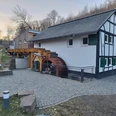 Dümmlinghauser Mühle Traditionelle Wassermühle mit hölzernem Wasserrad und Fachwerk, umgeben von Bäumen und Kopfsteinpflaster.
