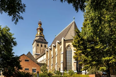 Saint Ursula St. Ursula's Church with its striking bell tower, surrounded by trees, under a clear sky.