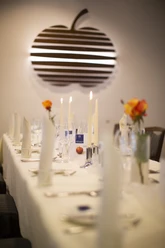 Gedeckter Tisch im Gütsel Ein festlich gedeckter Tisch mit weißen Tischtüchern, Kerzen und orangen Rosen in einem eleganten Raum.