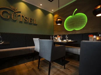 Gastraum Restaurant Gütsel Gemütliches Restaurant-Interieur mit stilvollem Dekor, modernen Möbeln und grüner Apfelbeleuchtung.