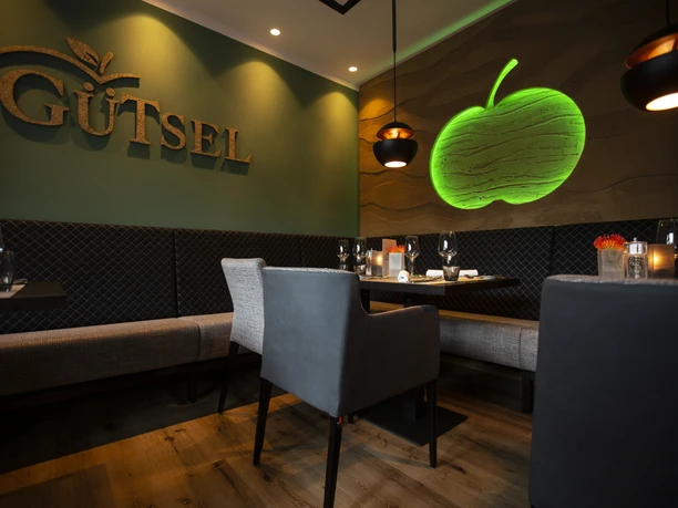 Gastraum Restaurant Gütsel Gemütliches Restaurant-Interieur mit stilvollem Dekor, modernen Möbeln und grüner Apfelbeleuchtung.