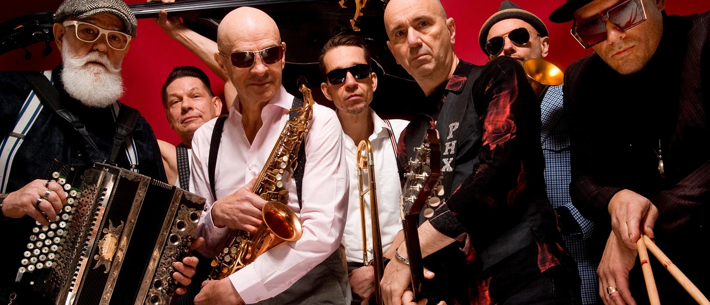 Musiker der Band Polkaholix in stilvollen Outfits mit Instrumenten wie Saxophon und Trompete.