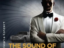 Ein Mann im weißen Smoking und schwarzer Fliege steht vor einem stilisierten Hintergrund mit Auto.