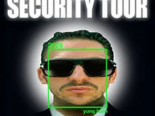 Porträt eines Mannes in schwarzem Anzug mit pinker Krawatte und Sonnenbrille. "Security Tour"-Schriftzug oben.