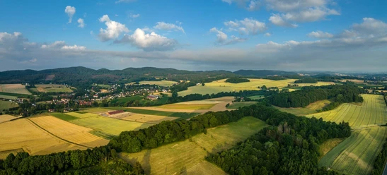 Panorama des Teutoburger Waldes mit weiten Feldern, sanften Hügeln und bewaldeten Abschnitten.